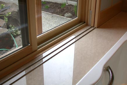 The upper tracking is wood and the lower tracking is a metal strip installed in the marble that engages a groove inlaid into the bottom of the window screen.