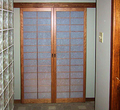 A barn door type tracking install, the shoji nest on the wall surface on either side of the doorway when open.